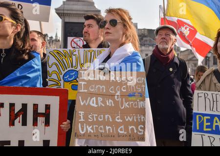 London, Großbritannien. 20.. März 2022. Ein russischer Protestler, der in die symbolische blau-weiße russische Flagge gehüllt ist und die rote Farbe entfernt hat, hält ein Antikriegszeichen. Auf dem Trafalgar-Platz versammeln sich weiterhin große Menschenmengen zur Unterstützung der Ukraine, während Russland seinen Angriff verstärkt. Kredit: Vuk Valcic/Alamy Live Nachrichten Stockfoto