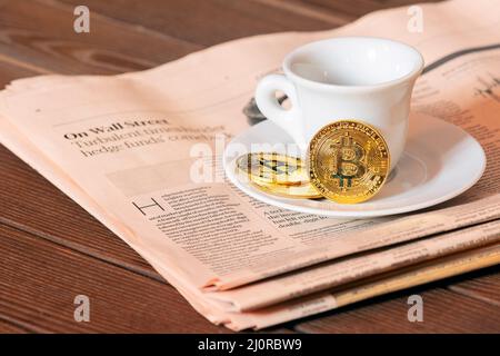 Morgenkaffee des Maklers an der Börse, schwarzer Kaffee und Bitcoin auf dem Hintergrund der Aktienkurskarte auf der Zeitung Stockfoto