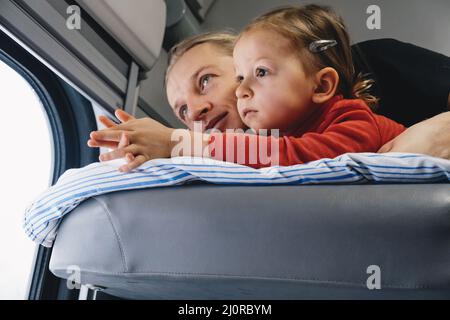 Vater mit Kind travalling in den Zug, Spaß zu genießen Szene durch Fenster, während auf der Eisenbahn zusammen im Schlafwagen fahren Stockfoto