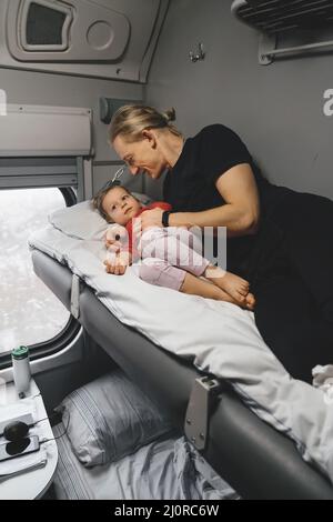 Vater mit Kind travalling in den Zug, Spaß zu genießen Szene durch Fenster, während auf der Eisenbahn zusammen im Schlafwagen fahren Stockfoto