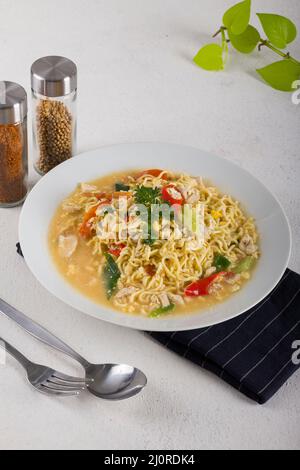 Eine Schüssel heiße Nudel mit gekochtem Ei, Huhn, Chili in einer weißen Schüssel auf weißem Hintergrund Textur schneiden Stockfoto