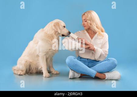 Frau, die ihre Kleidung mit einer Haftwalze vom Hundepelz säubert Stockfoto