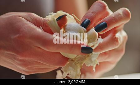Frau schält Knoblauch und Gemüse zum Kochen auf dem Küchentisch. Nahaufnahme der Hände. Echte, authentische Küche. Stockfoto