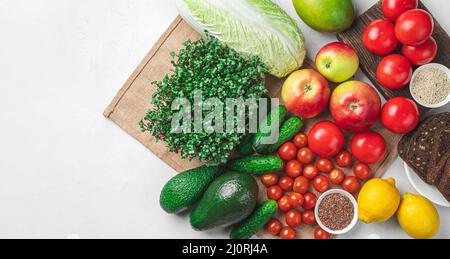 Eine Reihe von Produkten: Frisches Gemüse, Obst, Brot, Kräuter und Samen auf grauem Hintergrund. Gesunde Lebensmittel, die reich an Vitaminen und Mineralstoffen sind. Vegetarische Gerichte Stockfoto