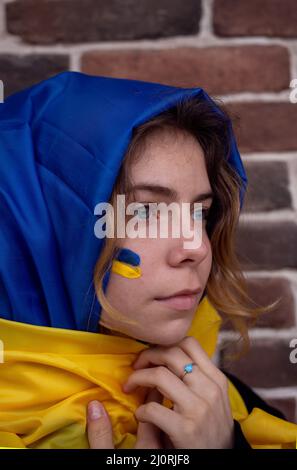 Porträt einer jungen Frau, in ein gelb-blaues Tuch gehüllt. Beendet den Krieg. Hoffnung und Glaube. Bleiben Sie in der Ukraine. Kriegsmüdigkeit und Hoffnungslosigkeit Stockfoto