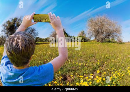 Der Junge macht Fotos auf einem Handy Stockfoto