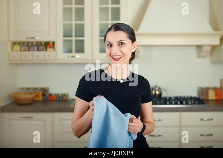 Junge glückliche gemischte Rasse Hausfrau mit Handtuch in der neuen Küche. Stockfoto