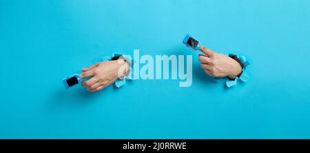 Am Zeigefinger wird ein Oximeter zur Messung des Sauerstoffs im Blut getragen, ein Teil der Hand ragt aus einem zerrissenen Loch in Th heraus Stockfoto