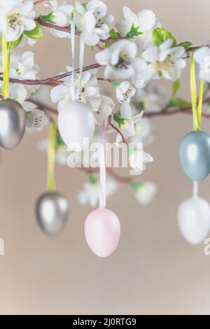 Farbige Ostereier, die mit weißen Blüten am Ast hängen Stockfoto