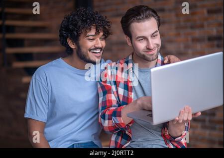 Männlicher Freiberufler und sein Freund beim Betrachen des Computerbildschirms Stockfoto