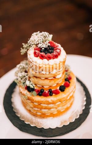 Hochzeit weißen Etagenkuchen mit Beeren und Blumen auf dem Tisch dekoriert Stockfoto