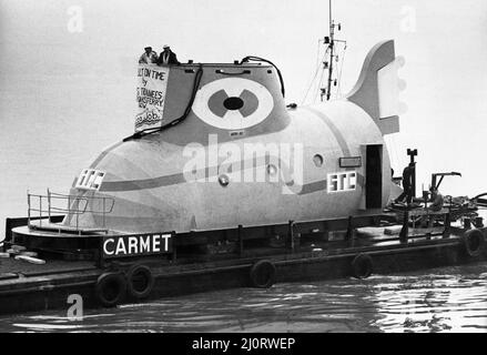 The Yellow Submarine in Liverpool, eine große Modelldarstellung des U-Bootes aus dem Animationsfilm Yellow Submarine, inspiriert vom gleichnamigen Lied auf dem Beatles-Album Revolver. Es wurde von einer Gruppe von etwa 80 Auszubildenden von Cammell Laird's Werft für die Ausstellung auf dem International Garden Festival in Liverpool im Jahr 1984 gebaut. Bild zeigt: Das U-Boot auf dem Fluss Mersey kurz vor dem Transport zum Messegelände nach dem Bau der Cammell Laird Werft in Birkenhead. 29.. Februar 1984. Stockfoto