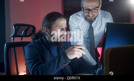 Zwei männliche Kollegen Mitarbeiter, die im Büro zusammenarbeiten und am Arbeitsplatz zusammenarbeiten. Teamwork-Konzept im Büro. Stockfoto