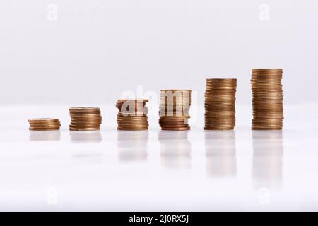 Jeder kleine Teil hilft. Studioaufnahme von Münzsäulen, isoliert auf weißem Hintergrund. Stockfoto