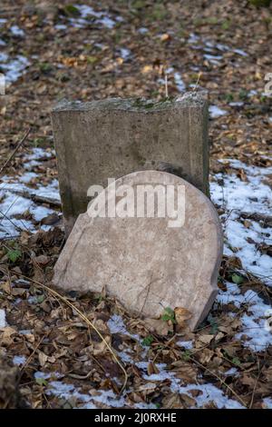 Alte alte alte verlassene jüdische Friedhof im Wald im Winter. Gealterte Grabsteine oder Grabsteine auf dem Friedhof. Stockfoto