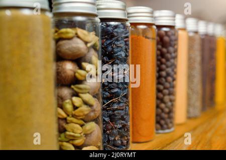 Nahaufnahme einer Reihe verschiedener Gewürze in transparenten Gläsern, selektiver Weichfokus. Stockfoto