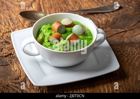 Cremige Erbsensuppe auf dunklem Holz Stockfoto