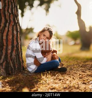 Manchmal braucht man nur eine Umarmung von seinem Bären. Porträt eines süßen kleinen Mädchens, das ihren Teddybären umarmt, während es draußen spielt. Stockfoto