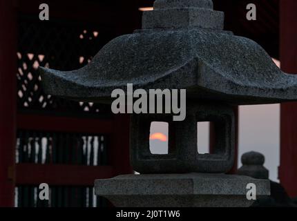 Der Blick auf den Sonnenuntergang durch die Feuerbox (hibukuro) der Steinlaterne. Japan Stockfoto