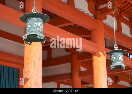 Hängende Kupferlaternen auf dem Hintergrund von Zinnobersäulen. Heian-jingu-Schrein. Kyoto. Japan Stockfoto