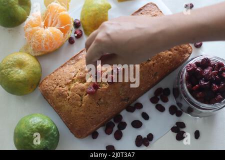 Orange Cranberry Brot. Ein schnelles Brot mit Orangengeschmack und getrockneten Preiselbeeren. Ein perfekter Begleiter zum Kaffee. Aufgenommen auf weißem Hintergrund mit getrockneten Stockfoto