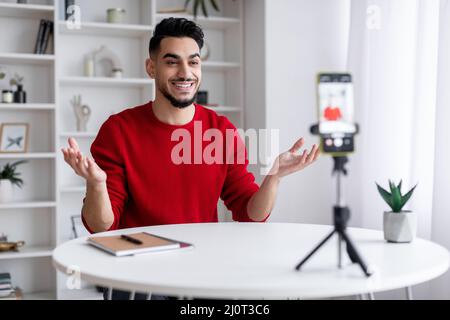 Junger Arabischer Blogger, Der Video Zu Hause Mit Smartphone Auf Stativ Aufzeichnet Stockfoto