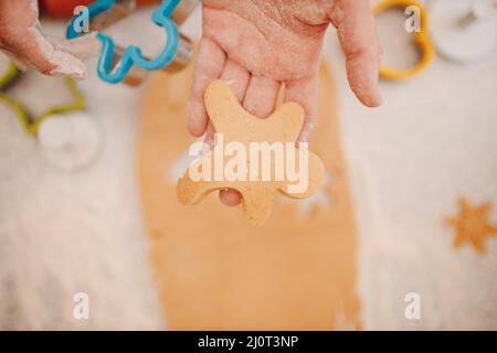 Frau Hände Formen Formen Kutter Ingwerteig und macht leckere weihnachten Ingwerkekse. Kochen und Dekorieren weihnachten desse Stockfoto