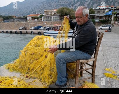 Der alte Fischer bereitet sein Fischernetz im Hafen von Plaka, Kreta, Griechenland vor Stockfoto