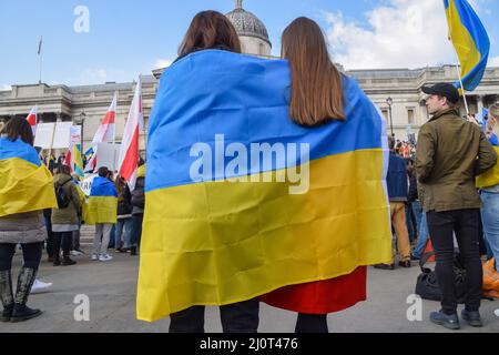 London, Großbritannien. 20.. März 2022. Demonstranten hüllen sich in eine ukrainische Flagge. Auf dem Trafalgar-Platz versammeln sich weiterhin große Menschenmengen zur Unterstützung der Ukraine, während Russland seinen Angriff verstärkt. Kredit: Vuk Valcic/Alamy Live Nachrichten Stockfoto