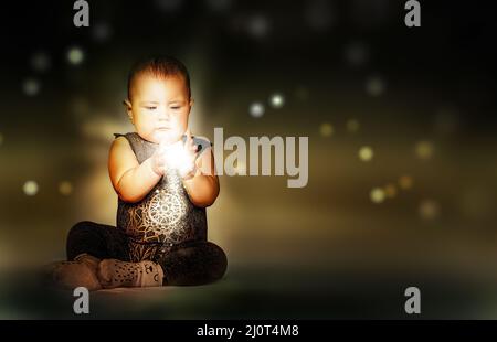 Leuchtendes Licht in den Händen von Little Cute Baby Stockfoto