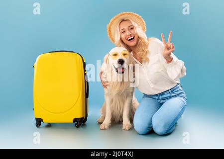 Glückliche Frau posiert mit Hund in Sonnenbrille bereit für den Urlaub Stockfoto