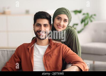 Die Ehegatten Aus Dem Nahen Osten Umarmen Sich Und Betrachten Die Zu Hause Sitzende Kamera Stockfoto