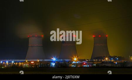 Minsk, Weißrussland - 11. November 2017: Kühltürme des thermischen Kraftwerks. Dampf steigt auf. Nachtansicht. Stockfoto