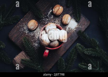 Gebackenes, nussförmiges Dessert in einem roten Keramikbecher, bestreut mit Puderzucker, Draufsicht Stockfoto