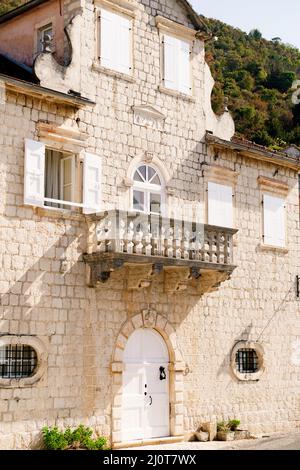 Fassade eines Steingebäudes mit Fensterläden und Balkon. Perast, Montenegro Stockfoto