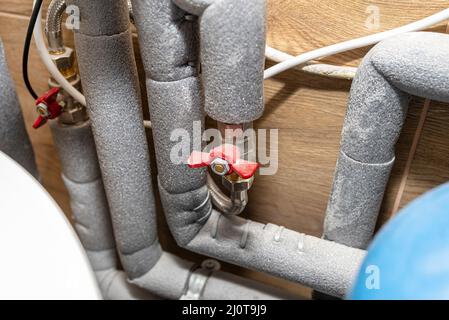 Geschlossene Wasserventile zum Ausgleich des Wasserdrucks in einem Gaskessel in einem modernen Heizraum mit Keramikfliesen. Stockfoto