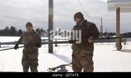 ÄSCHEN, mich. – Stabsmitarbeiter der US-Armee Joshua McKee (links), ein nicht beauftragter Offizier der Feuerkontrolle, und SPC der US-Armee. Michael Fleming (rechts), ein Spezialist für die Brandrichtung, beide zusammen mit Bravo Battery, 1. Bataillon, 182. Field Artillery Regiment, Michigan National Guard, installieren während des Northern Strike 22-1 am 21. Januar 2022 einen nahezu senkrecht eintretenden Skywave-Satelliten. Northern Strike 22-1 („Winterstreik“) ist eine vom National Guard Bureau gesponserte Übung, die Dienstmitglieder aus mehreren US-Bundesstaaten und Partnereinheiten vom 21. Bis 30. Januar 2022 im Camp Greyling Joint Maneuver Training Cent vereint Stockfoto