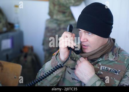 Personal Sgt. Brian Hill, der Charlie Company „Fighting Aces“ zugewiesen wurde, von 2. Bataillon, 34. Panzerregiment, 1. Panzerbrigade Combat Team, 1. Infanterie Division, kommuniziert mit Bradley-Besatzungen vom Turm aus, während sie Schützenoperationen im Konotop Range, Drawsko Pomorskie Training Area, Polen, 22. Januar 2022 durchführen. Vom Reichweitenkontrollturm aus bewerten Soldaten, die dem Pfadfinderzug, der Hauptverwaltung und der Hauptquartiersgesellschaft, dem Bataillon 2., dem Panzerregiment 34., dem Kampfteam der Panzerbrigade 1. und der Infanteriedivision 1. zugeordnet sind, die Leistung der Charlie Company. (USA Armeefoto von Sgt. Tara Stockfoto