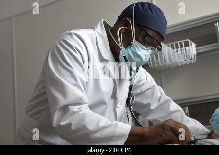 BUFFALO, N.Y. – der US-Navy LT. Ivo Teneng, ein Arzt für Innere Medizin, der dem Walter Reed National Medical Center, Navy Medicine Readiness and Training Command, Bethesda, Maryland, zugewiesen ist, überprüft die Herzfrequenz und Atmung eines Patienten und unterstützt die COVID-Reaktionsoperationen im Erie County Medical Center in Buffalo, New York, Januar 23, 2022. Das U.S. Northern Command setzt sich über die U.S. Army North weiterhin für die flexible Unterstützung des Verteidigungsministeriums für die COVID-Reaktion der gesamten Regierung ein. (USA Armee-Foto von SPC. Ashleigh Maxwell) Stockfoto