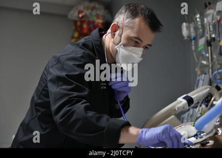 BUFFALO, N.Y. – der US Navy LT. Jeffrey Stroud, eine Krankenschwester für die Intensivmedizin, die dem Walter Reed National Medical Center, Navy Medicine Readiness and Training Command, Bethesda, Maryland, zugewiesen ist, überprüft die Herzfrequenz und das Atemmuster eines Patienten und unterstützt die COVID-Reaktionsoperationen im Erie County Medical Center in Buffalo, New York, Januar 23, 2022. Das U.S. Northern Command setzt sich über die U.S. Army North weiterhin für die flexible Unterstützung des Verteidigungsministeriums für die COVID-Reaktion der gesamten Regierung ein. (USA Armee-Foto von SPC. Ashleigh Maxwell) Stockfoto