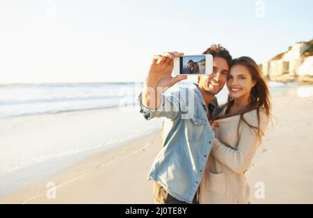 Liebe am Strand. Aufnahme eines liebevollen jungen Paares, das am Strand ein Selfie gemacht hat. Stockfoto