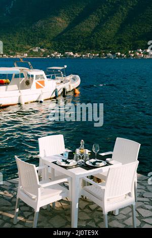 Gedeckte festliche Tisch mit Stühlen steht auf dem Pier am Meer Stockfoto