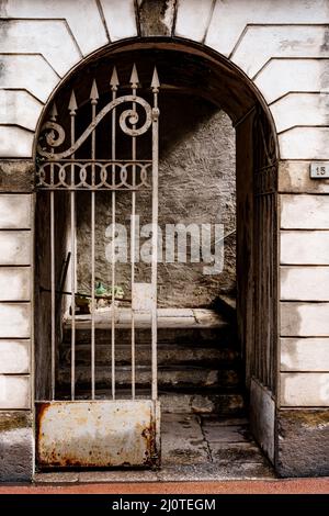 Schmiedeeisernes Tor mit scharfen Zacken im gewölbten Eingang zum Gebäude Stockfoto