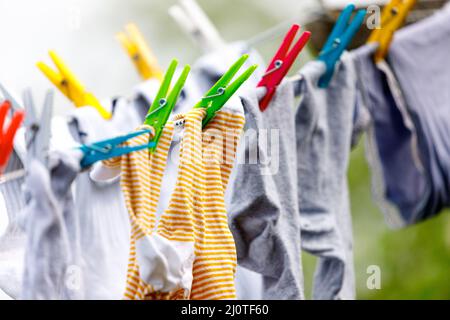 Die Kleidung ist mit mehrfarbigen Klammern auf einem grünen Feld übersät Stockfoto