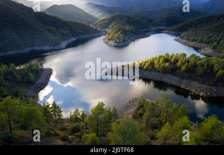 Luftdrohnenansicht eines Staudamms voller Wasser im Wald. Lefkara Reservoir Larnaka Zypern Stockfoto