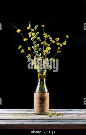 Bouquet von blühenden Ästen aus Weide und Dogwood in einer Vase auf dem Tisch auf schwarzem Hintergrund Stockfoto