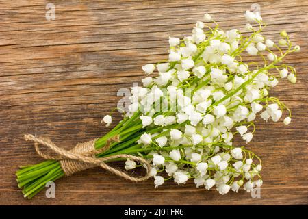 Vintage Bouquet von wilden Blumen, die weißen duftenden Lilien auf das Tal auf einem alten Holzbrett closeup Stockfoto