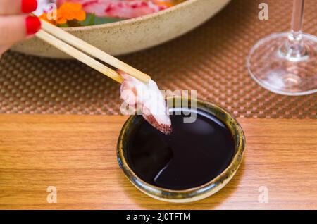Frau, die leckeres Sushi isst, Nahaufnahme von Essstäbchen Stockfoto