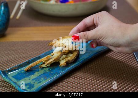 Frau, die geröstete Brotscheiben auf einem wunderschön dekorierten Teller nahm Stockfoto