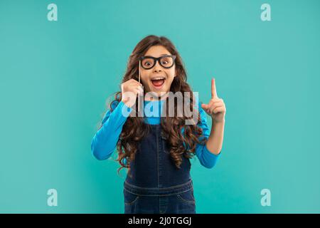 Begeistert inspiriert mit Idee Kind mit lockigen Haaren halten Partei Accessoire der Brille, Inspiration Stockfoto